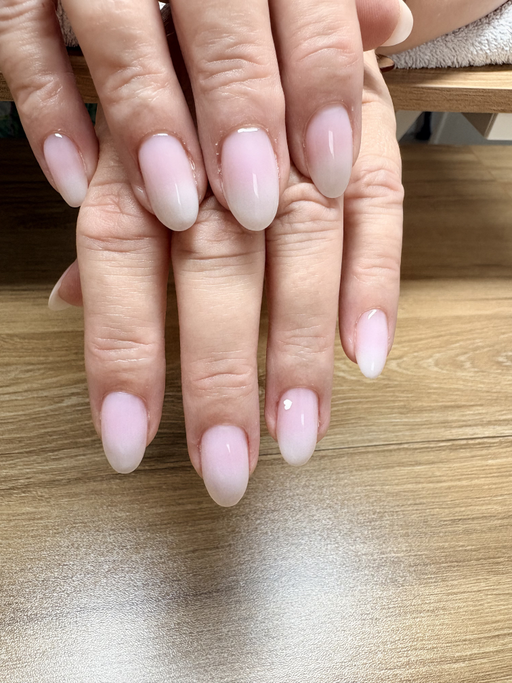 Ongles amande de longueur moyenne, rose pâle fondu vers une pointe blanche, finition brillante.