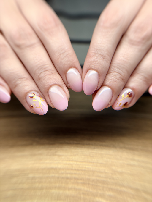 Ongles amande de longueur moyenne, rose poudré fondu vers le blanc, deux ongles ornés de feuille d’or et de petites touches bordeaux, les deux mains côte à côte.